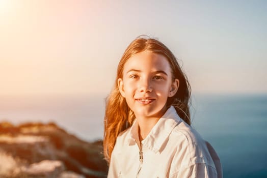 Brown-haired young romantic teenager girl corrects long hair on beach at summer evening wind