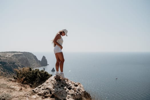 Woman travel sea. Young Happy woman in a long red dress posing on a beach near the sea on background of volcanic rocks, like in Iceland, sharing travel adventure journey