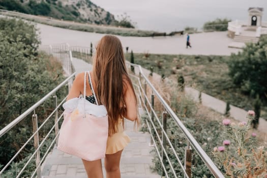 Woman travel sea. Happy tourist taking picture outdoors for memories. Woman traveler looks at the edge of the cliff on the sea bay of mountains, sharing travel adventure journey.