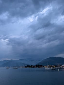 Falling dusk on a bay with sailing yachts at the foot of a mountain range. High quality photo