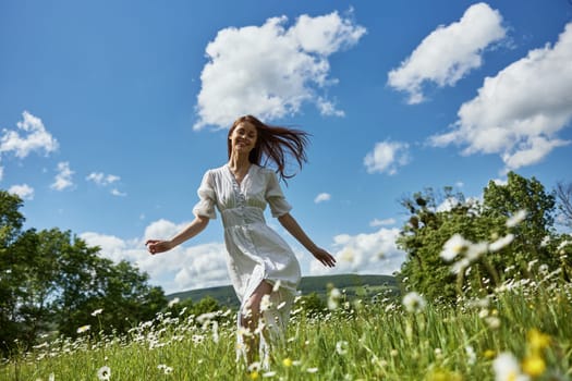 a happy woman in a light dress runs through a chamomile field against a clear sky. High quality photo