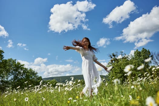 a happy woman in a light dress runs through a chamomile field against a clear sky. High quality photo