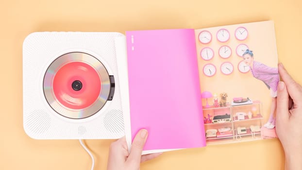 Hands holding Twice Between 1 and 2 mini Album photobook on yellow. Music CD player. South Korean girl group Twice. Space for text. Gatineau, QC Canada - December 27 2022
