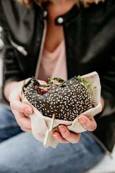 Close up of woman hands holding delicious organic salmon vegetarian burger on open air beer an burger urban street food festival in Ljubljana, Slovenia