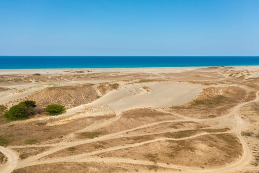 Sandy beach and blue ocean. Paoay Sand Dunes, Ilocos Norte, Philippines.