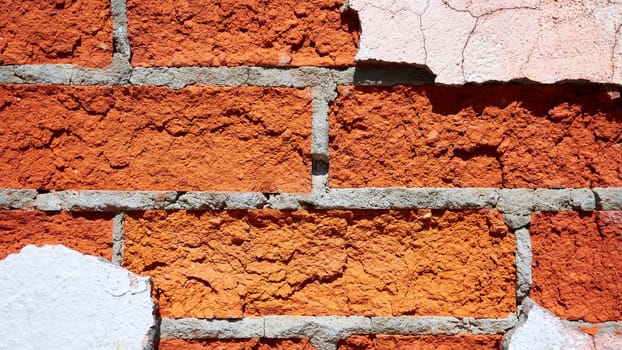 Texture of a red brick wall with pieces of peeled off plaster