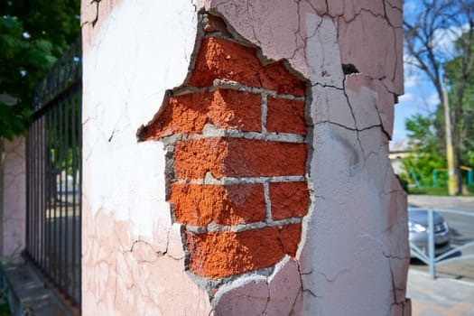 Close-up corner of a brick fence with crumbling plaster