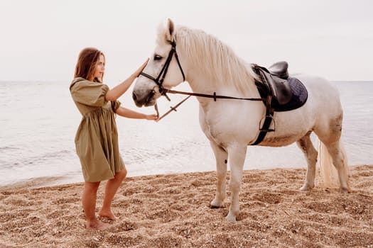 A white horse and a woman in a dress stand on a beach, with the sky and sea creating a picturesque backdrop for the scene