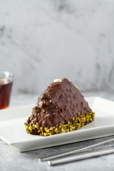 Dessert Cake from Malaga on stone table. Cake with banana inside, covered with chocolate sauce and hazelnuts