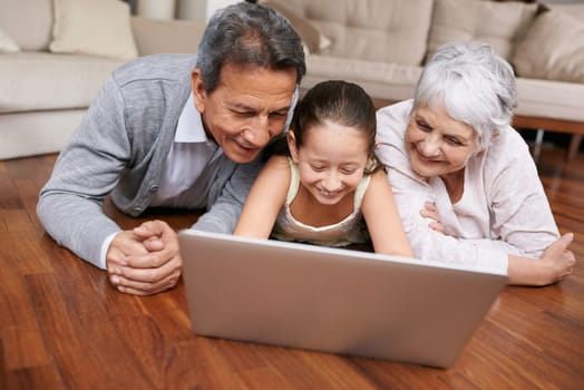 Laptop, floor or grandparents with happy child for movie streaming online subscription in retirement at home. Girl, relaxing together or grandmother watching videos on internet with a senior old man.