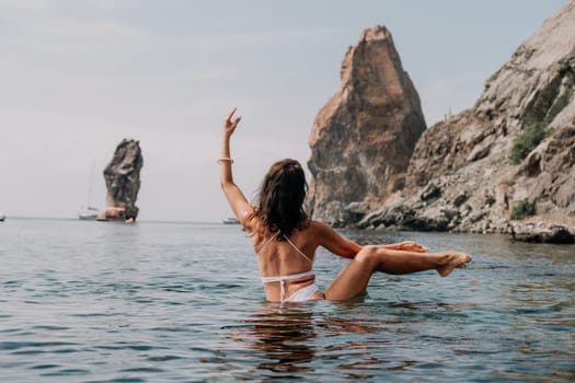 Young woman with black hair, fitness instructor in pink sports leggings and tops, doing pilates on yoga mat with magic pilates ring by the sea on the beach. Female fitness daily yoga concept