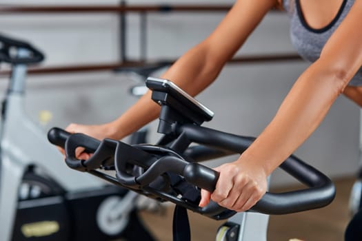 Strong female hand on a stationary bike in the gym
