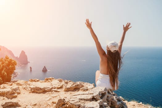 Woman travel sea. Young Happy woman in a long red dress posing on a beach near the sea on background of volcanic rocks, like in Iceland, sharing travel adventure journey