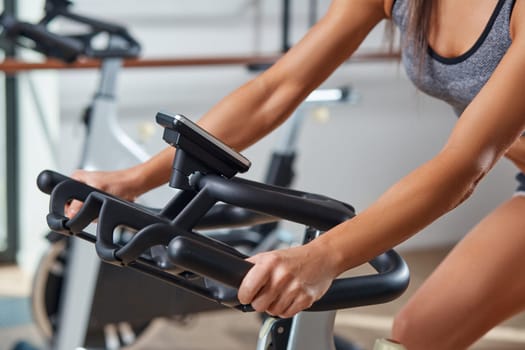 Strong female hand on a stationary bike in the gym