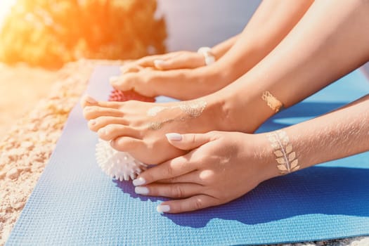 Middle aged well looking woman with black hair doing Pilates with the ring on the yoga mat near the sea on the pebble beach. Female fitness yoga concept. Healthy lifestyle, harmony and meditation.