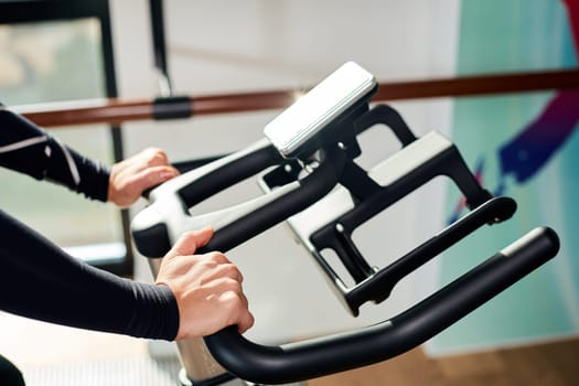 Strong female hand on a stationary bike in the gym