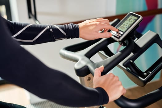 Strong female hand on a stationary bike in the gym