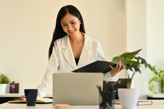 Confident female analyst in stylish suit watching online webinar on laptop screen. Business, communicating and technology.