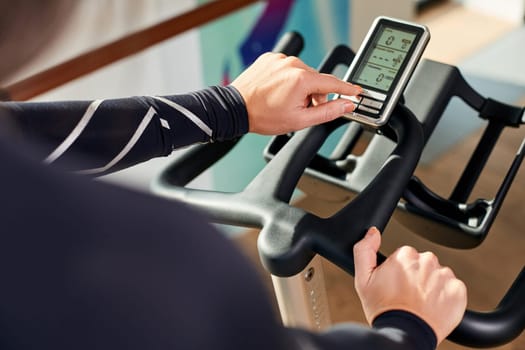 Strong female hand on a stationary bike in the gym