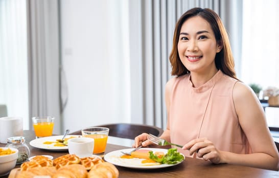 Woman eat fresh breakfast served food with beverage before go to work in the morning at home, Asian young female sitting kitchen table food having eating healthy breakfast at home