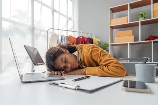 designer woman sleeping on desk in atelier after exhausted from designing clothes.