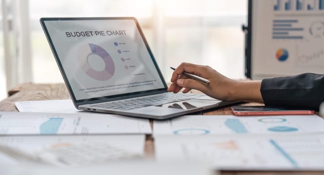 Asian businesswoman sit at their desks at office and calculate financial graphs showing results about their investments, plan a successful business growth process, diagrams on screen.