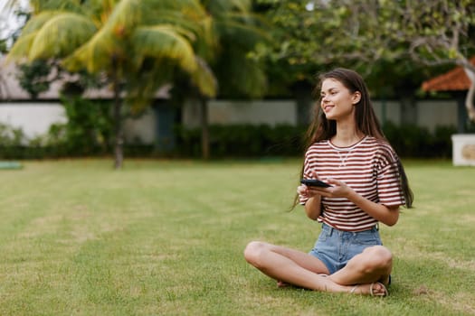 woman browsing palm phone spring smartphone beautiful grass app tree nature blogger cellphone lifestyle smiling adult happy outside outdoor smile talk park