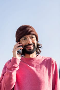 stylish young man in pink jersey smiling happy talking on smart phone, concept of modern lifestyle and technology of communication, copy space for text