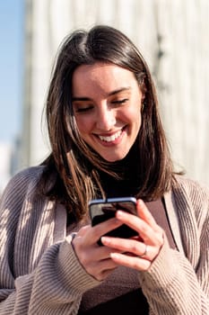 young woman smiling happy while texting on her mobile phone, concept of modern lifestyle and technology of communication