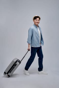 Happy young Asian tourist man holding baggage going to travel on holidays