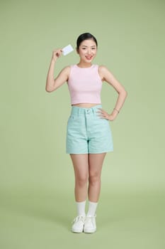 Young asian woman over blue background holding a credit card