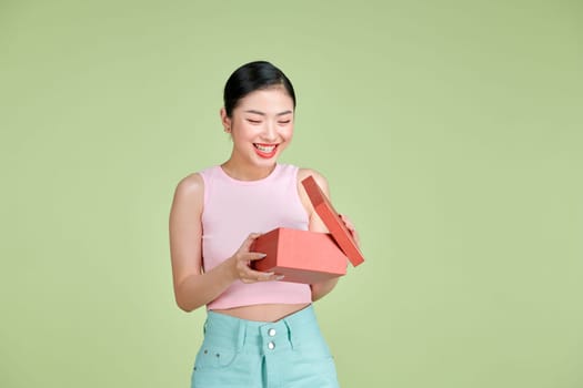 Portrait of a happy smiling girl opening a gift box isolated over green background