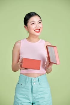 Happy young woman opening present for Valentine's Day on green studio background, 