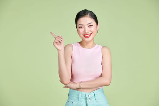 Portrait of Asian beautiful young woman pointing one hand with finger on side with smile face. 