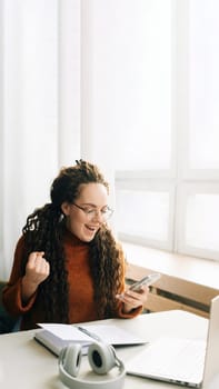 Young happy lucky woman student feeling excited winner holding cellphone using mobile phone winning online, receiving great news or sms offers on a smartphone, getting a new job celebrating success
