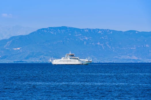 A small car ferry boat sailing on a calm blue sea on a bright summer day in Greece.