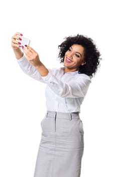 Beautiful brunette woman in classic white shirt and skirt make selfie on the phone. White background. Isolated