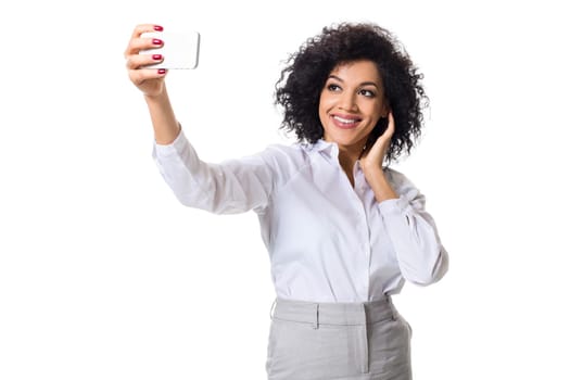 Beautiful brunette woman in classic white shirt and skirt make selfie on the phone. White background. Isolated