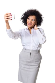 Beautiful brunette woman in classic white shirt and skirt make selfie on the phone. White background. Isolated