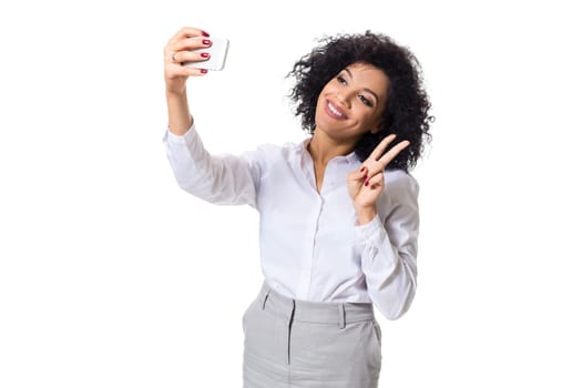 Beautiful brunette woman in classic white shirt and skirt make selfie on the phone. White background. Isolated