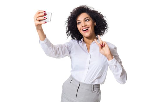 Beautiful brunette woman in classic white shirt and skirt make selfie on the phone. White background. Isolated