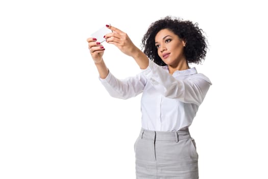 Beautiful brunette woman in classic white shirt and skirt make selfie on the phone. White background. Isolated