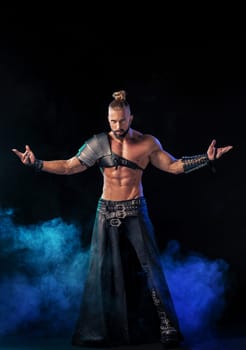 Young and muscular man performing a theatrical pose on a stage. Very sexy man in stage costume