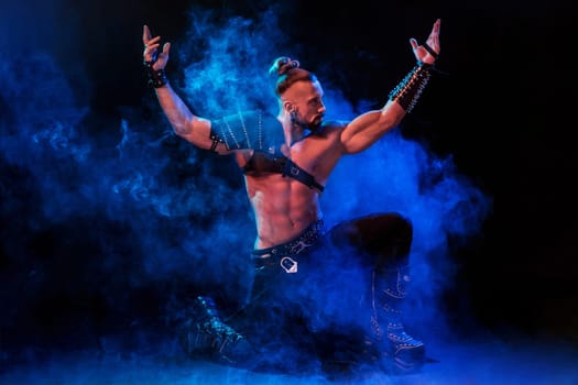 Young and muscular man performing a theatrical pose on a stage. Very sexy man in stage costume