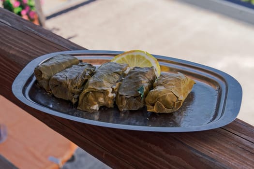 Served dolmades, wrapped in little rolls, a traditional dish with stuffed vine leaves, served with a slice of lemon.