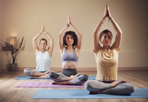 Yoga is energy. Full length shot of a young group of women sitting together and meditating after an indoor yoga session