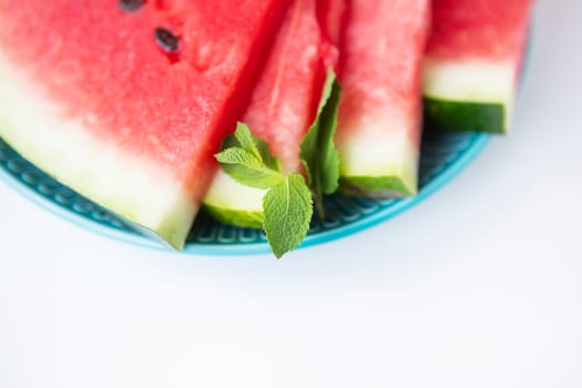 Close-up of fresh slices of watermelon along with mint leaves lie on a plate. Summer food