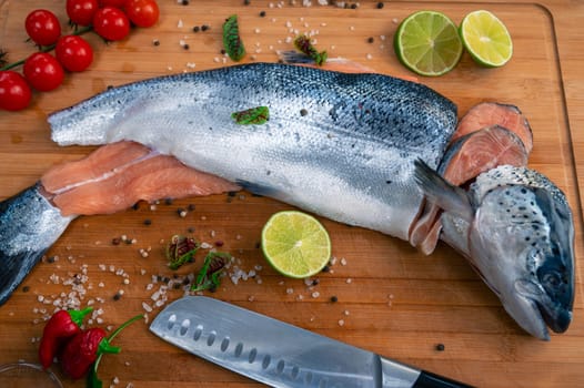 Fresh raw salmon fish on the kitchen wooden board with spices and lime
