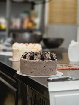 preparing brown frosted icing cup cake with cookies on top in the kitchen