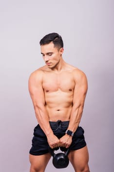 Hispanic male athlete working out with kettlebell on a grey background. Crossfit workout theme.